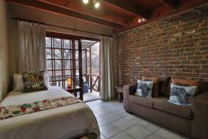 Un dormitorio con una cama y una pared de ladrillo. en Lion Den, en Marloth Park