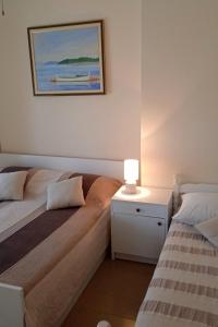 a bedroom with two beds and a table with a lamp at Apartments by the sea Cove Ostricka luka, Rogoznica - 11451 in Zaglavice