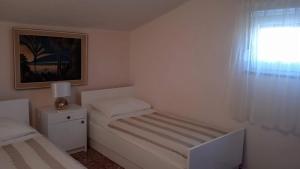 a small white bedroom with a bed and a window at Apartments by the sea Cove Ostricka luka, Rogoznica - 11451 in Zaglavice