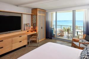 a bedroom with a bed and a television and a balcony at Turtle Bay Resort in Kahuku