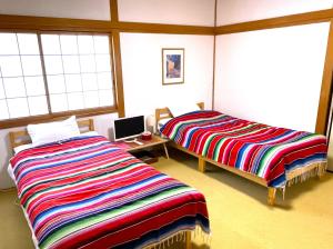 2 Betten in einem Zimmer mit 2 Fenstern in der Unterkunft Takamatsu Guest House Akane in Takamatsu
