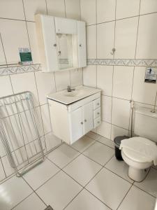 a white bathroom with a sink and a toilet at Encantos do Lázaro in Ubatuba