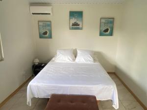 a bedroom with a white bed and a brown stool at TAHITI - Bungalow Toah Piti in Taravao