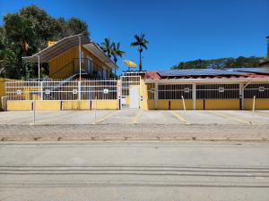 um edifício amarelo com um parque de estacionamento em frente em Encantos do Lázaro em Ubatuba