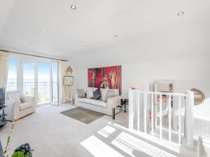 a living room with white furniture and a large window at Heath Lodge in Brixham