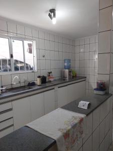 uma cozinha com paredes de azulejos brancos e uma bancada em Quarto individual masculino em São José do Rio Preto
