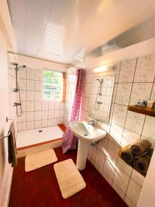 La salle de bains est pourvue d'un lavabo, d'une douche et d'une baignoire. dans l'établissement RAIATEA - Studio TUMARAA, à Uturoa