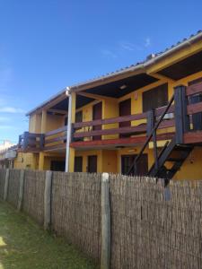 a yellow house with a fence in front of it at Aparts Complejo Arinos in Aguas Dulces