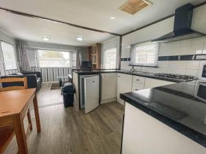 a kitchen with white appliances and a table in a room at Homely Caravan Just A Short Walk To Hembsy Beach In Norfolk Ref 00036ba in Hemsby
