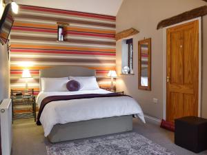 a bedroom with a bed and a striped wall at Barn End in Pooley Bridge