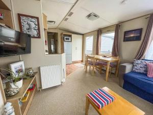a living room with a blue couch and a table at Brilliant Caravan With Wifi And Decking Near Pakefield Beach Ref 68040cr in Lowestoft