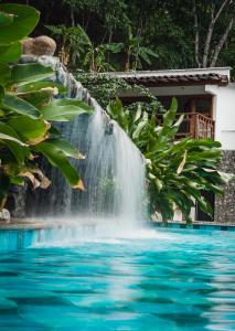 a waterfall over a pool with blue water at Bio Rio Hotel in San Jerónimo