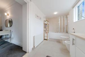 a white bathroom with a tub and a toilet and a sink at Knightsbridge Two Bed Apartment in London