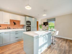 a kitchen with white cabinets and a kitchen island at Lakeside Cottage in Lanchester