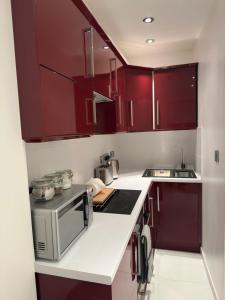 a kitchen with red cabinets and a microwave at St Paul's Farringdon Longstay Cozystay in London