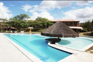 a large swimming pool with a straw umbrella at Loc10flats 3 Quartos - Residencial Monte Castelo in Bezerros