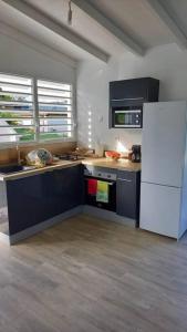 eine Küche mit einem weißen Kühlschrank und einem Herd in der Unterkunft Le Gîte Petit colibri in Sainte-Rose