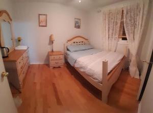 1 dormitorio con cama blanca y suelo de madera en Cozy Place-Laid Back, en Mississauga