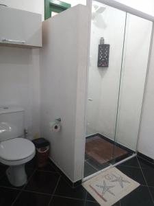 a bathroom with a toilet and a glass shower stall at Kitnet da Elô in Tramandaí