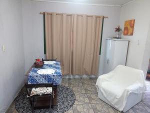 uma sala de estar com uma mesa e uma cadeira em Kitnet da Elô em Tramandaí