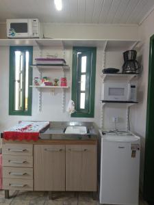 una pequeña cocina con fregadero y nevera. en Kitnet da Elô en Tramandaí