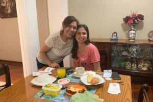 Zwei Frauen sitzen mit Essen an einem Tisch. in der Unterkunft Habitación en Primer Piso con baño privado in Lima