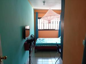 - une petite chambre avec un lit et une fenêtre dans l'établissement RÉSIDENCE TCHAMS, à Yaoundé