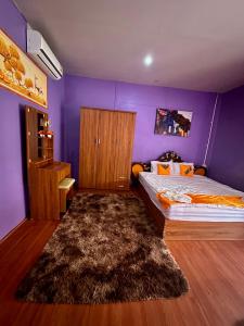 um quarto com uma cama e uma parede roxa em Heaven Guesthouse em Pakse