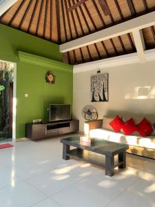 sala de estar con sofá y TV en De' Bharata Bali Villas, en Seminyak