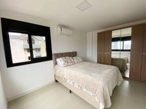1 dormitorio con cama y ventana en Apto central e próximo à praia, en Torres