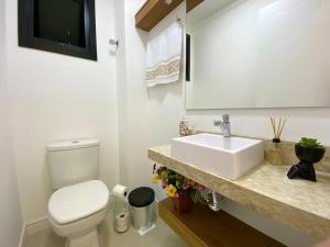 een badkamer met een wit toilet en een wastafel bij Apto central e próximo à praia in Torres