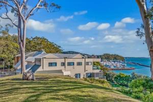 a house on a hill with a view of the water at The Poplars, Pool Access Getaway in Nelson Bay