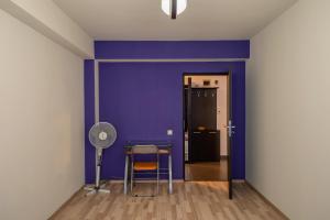 Camera con parete viola, tavolo e ventilatore. di Quiet 3-Room Apt - 2 Parking Spaces - 5 Min Bus a Floreşti