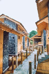 a row of wooden buildings with a walkway between them at Chien's Lodge Du Gia in Làng Cac