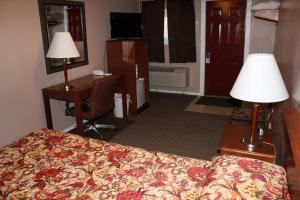 a hotel room with a bed and a desk and a lamp at The Village Motel in Steamboat Rock +1 photo