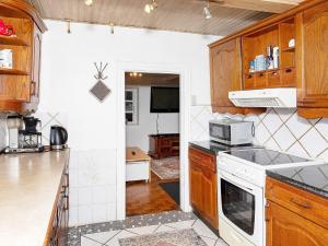 a kitchen with wooden cabinets and a white stove top oven at Holiday home Løgstør IX in Løgstør