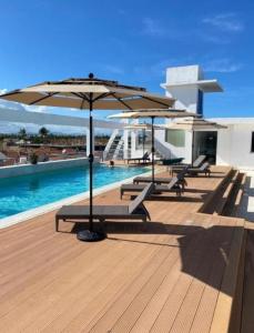 a row of benches with umbrellas next to a pool at Ducassi - Sol Caribe playa los corales in Punta Cana