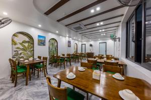 CatBa Green Pearl Hotel في كات با: غرفة طعام مع طاولات وكراسي خشبية