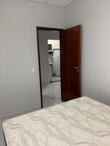 a bedroom with a bed and a door leading to a kitchen at Apartamento Maranduba in Ubatuba
