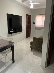 Apartamento Maranduba في أوباتوبا: غرفة معيشة مع تلفزيون بشاشة مسطحة على الحائط