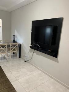 TV de pantalla plana grande colgada en la pared en Apartamento Maranduba en Ubatuba