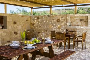 un patio con mesa, sillas y pared de piedra. en Villa Ydria, en Chavriáta