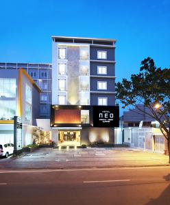 a tall building with a sign in front of it at Hotel NEO Cirebon by ASTON in Cirebon