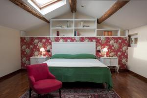 a bedroom with a bed and a red chair at Villa Al Sicomoro in Grezzana
