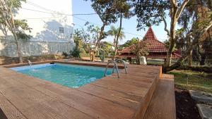 een zwembad met een houten terras naast een huis bij Villa Ohana Batu in Batu