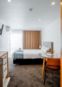 Pokój hotelowy z łóżkiem, stołem i biurkiem w obiekcie Merivale Court Motel & Apartments w mieście Christchurch