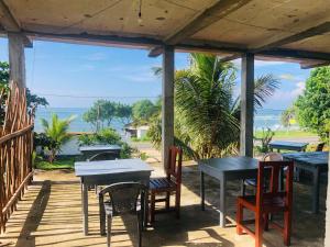 a patio with tables and chairs and a view of the ocean at Laguna Surfing Stay in Midigama