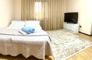 a bedroom with a bed with a television and towels at Town House, metro Raiymbek in Almaty