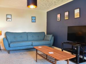 salon z niebieską kanapą i telewizorem w obiekcie Oak Bank w mieście Great Blencow