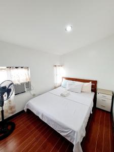 Schlafzimmer mit einem weißen Bett, einem Schreibtisch und einem Fenster in der Unterkunft Furnished House in Calapan City Subdivision near ROBINSONS Mall L33 in Calapan